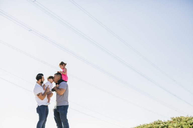 Family Of Four Standing Together Outside With Big Sunny Sky